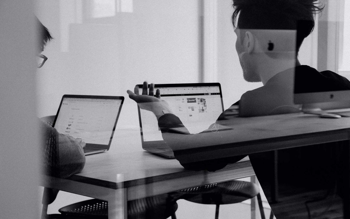 two people sitting in an office looking at their laptops